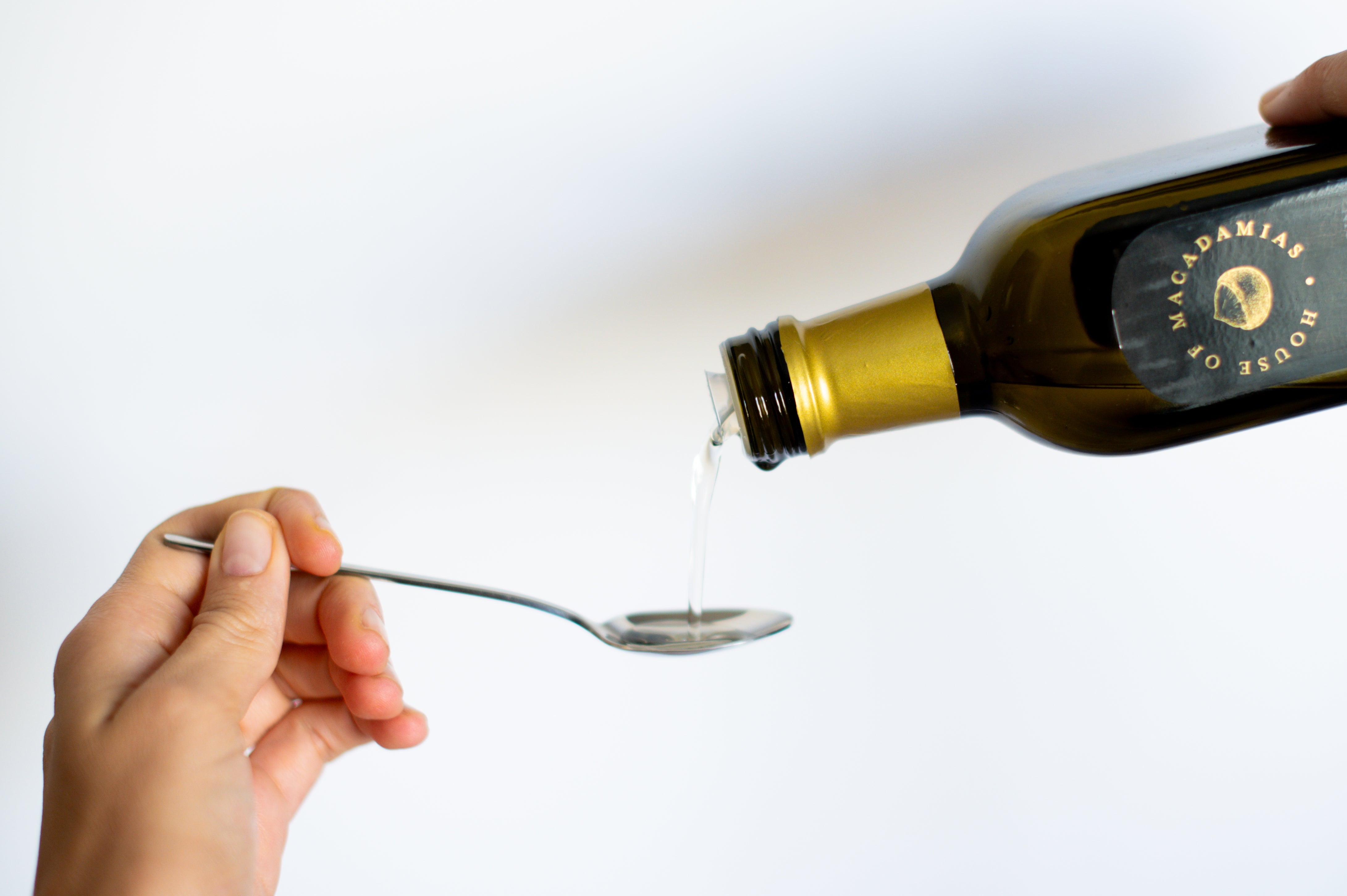 macadamia oil being poured into a spoon as a heart-healthy ingredient for longevity