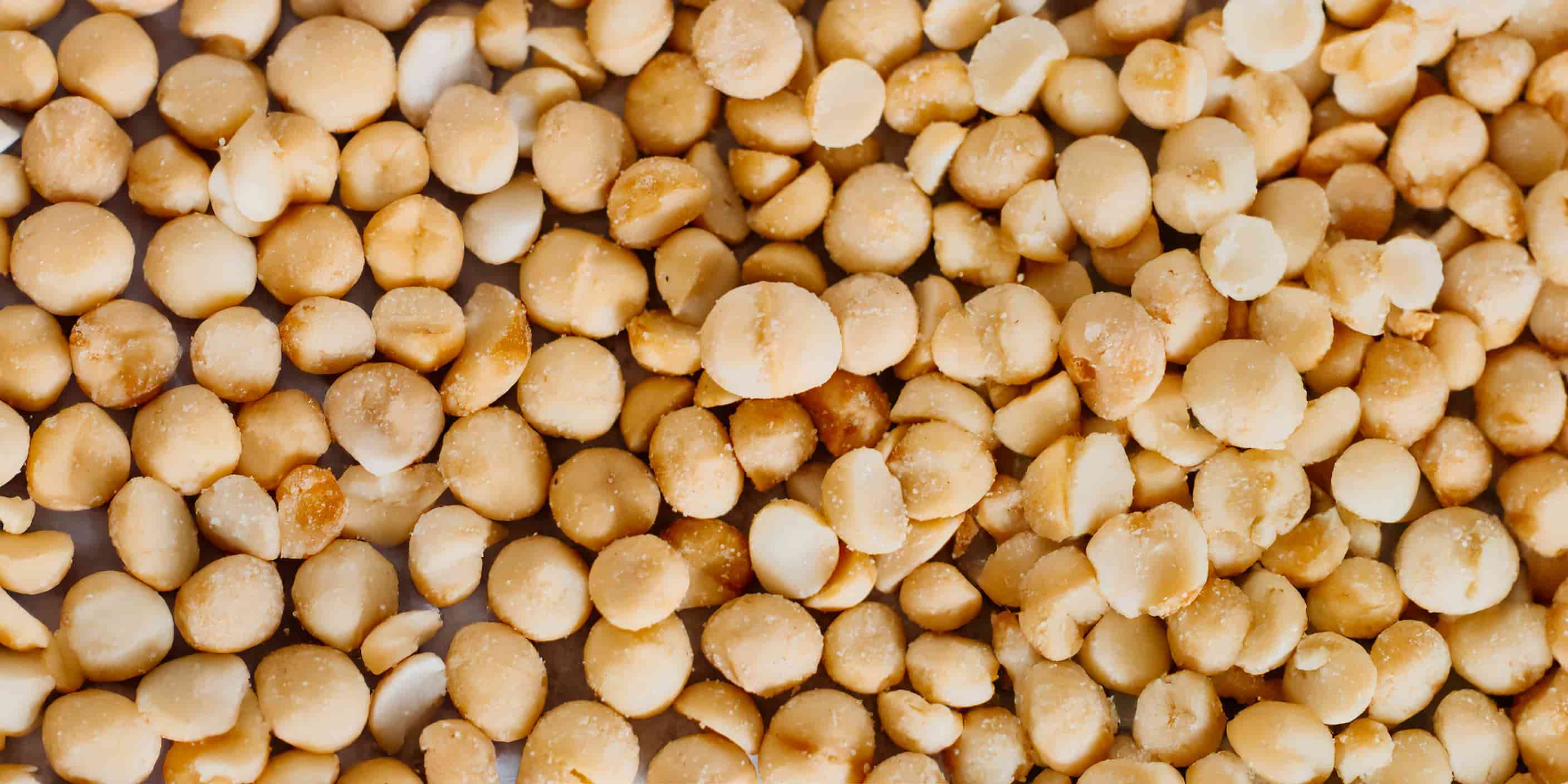 A close up of macadamia nuts, showcasing them as a buttery, salty snack that is packed with health benefits from heart-health to collagen boosting nutrients.