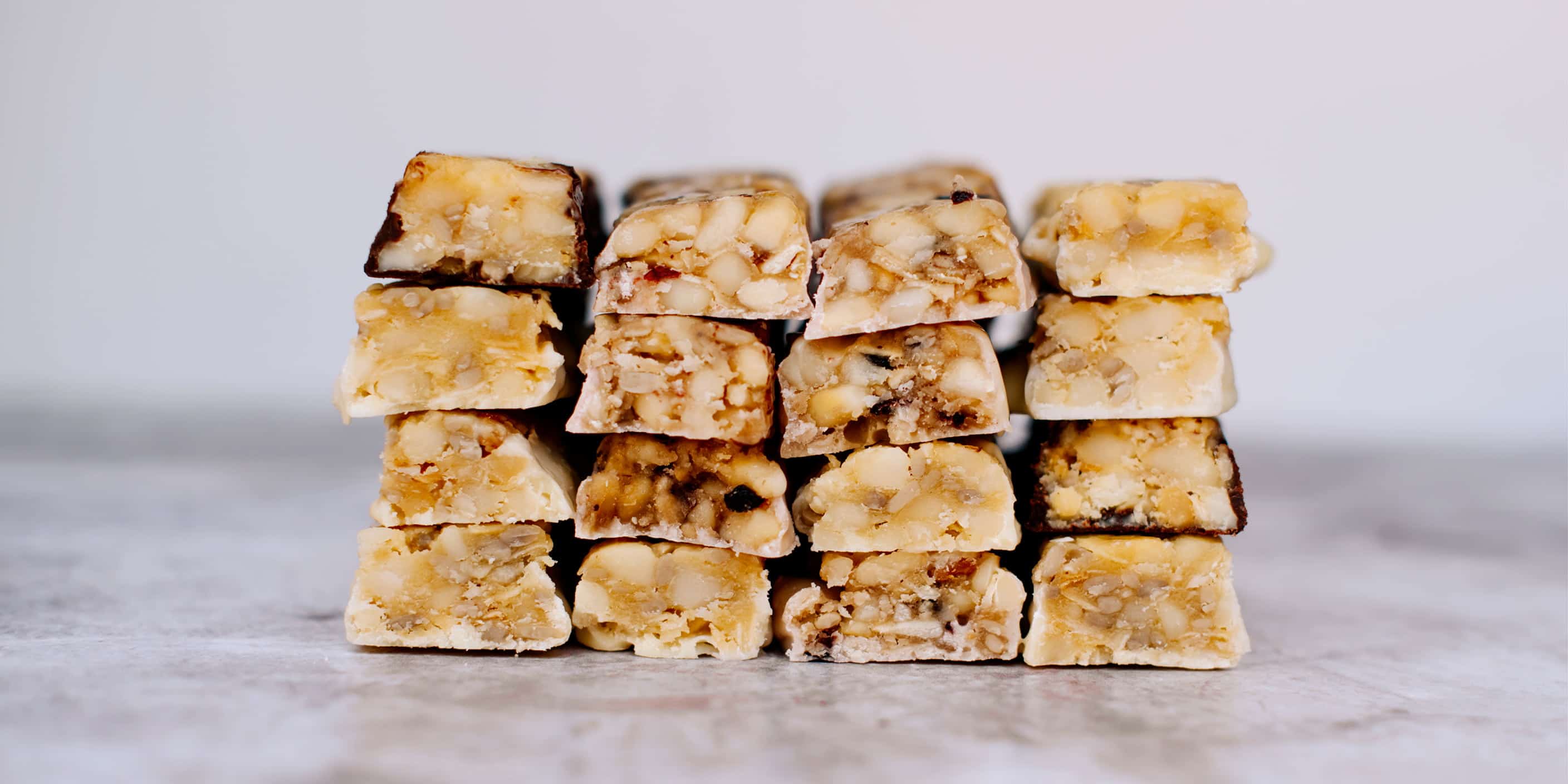 Macadamia nut bars stacks on top of each other. Superfood snack bars, sugar-free, natural ingredients, and vegan chocolate.