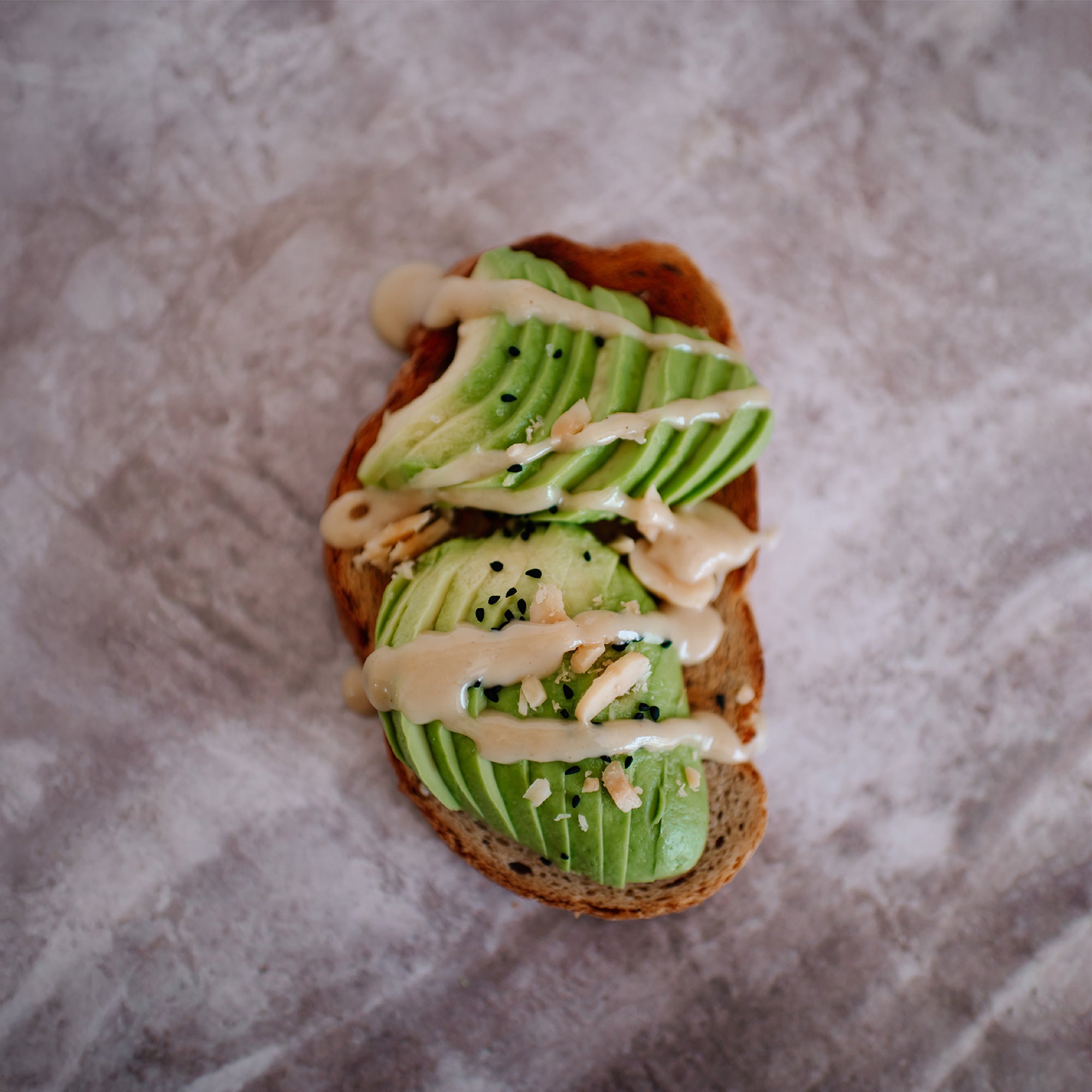 Sea Salt Macadamia Nut Butter drizzled over seasoned avocado on sourdough toast