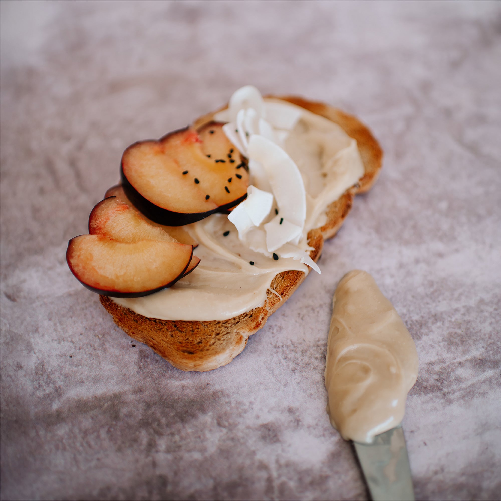House of Macadamias White Chocolate Macadamia Nut Butter spread on sourdough toast topped with assorted fruit slices